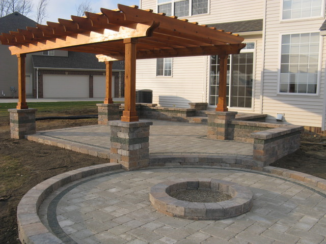 Patio with pergola, fire pit, and brick pavers. Outdoor backyard with a house in the background.