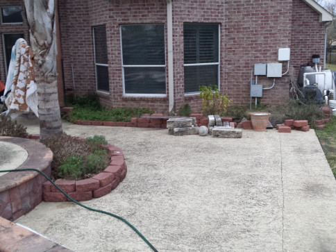Backyard patio with brick border, palm tree, and brick house.