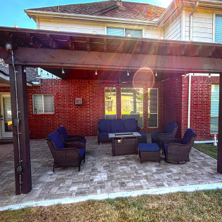 Outdoor patio with brick wall, pergola, and blue seating.