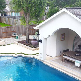 Outdoor pool with white cabana, table, and seating. Yard with fence and trees.