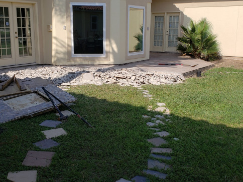 Backyard patio under construction with exposed concrete. A stepping stone path leads to it.