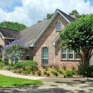 Brick house with a landscaped yard and a walkway on a sunny day.