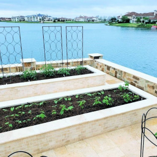 Raised garden beds overlooking a lake, with metal trellises and lush greenery.