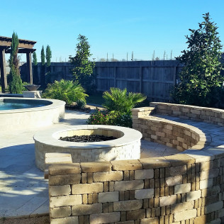 Outdoor patio with circular fire pit, pool, and curved stone walls.