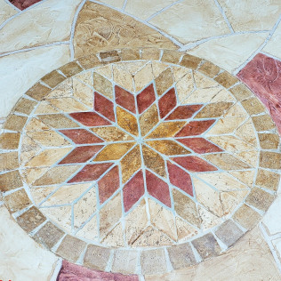 Circular stone mosaic with a central starburst design in earth tones.
