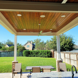 Covered patio with a wood ceiling, outdoor furniture, and a view of a grassy backyard.