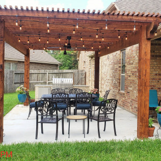 Patio with wood pergola, string lights, and seating for dining.