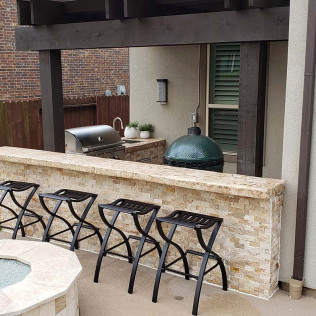Outdoor kitchen with a grill, Big Green Egg, countertop, and seating.