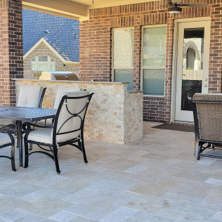 Outdoor patio with table, chairs, brick wall, and built-in grill area.