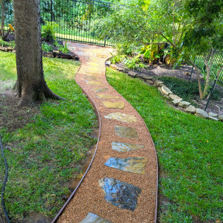 Stone path winding through a green, grassy yard.