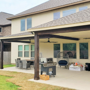 Outdoor patio with a grill, dining set, and seating under a covered roof.