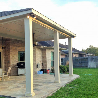 Patio with a covered seating area, brick wall, and green lawn.