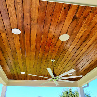 Wooden ceiling with recessed lights and a ceiling fan, viewed from below.