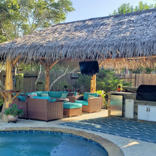 Outdoor living space with a pool, tiki hut, seating area, grill, and TV.