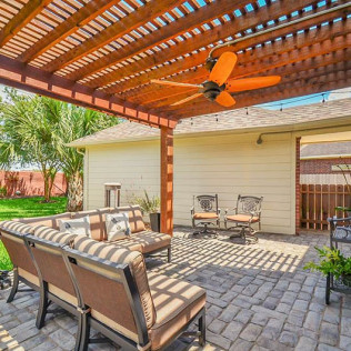 Patio with a wooden pergola, outdoor furniture, and ceiling fan.