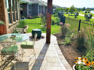 Patio with table, chairs, and garden; overlooks a grassy area and lake.