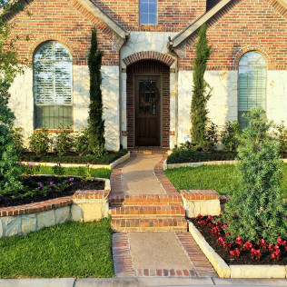 Brick home with path, landscaping, and arched doorway.