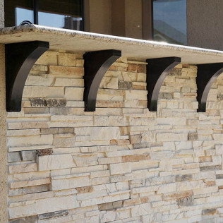 Stone wall with black brackets supporting a counter.