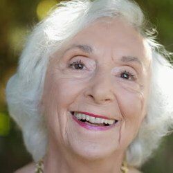 An elderly woman with white hair is smiling for the camera.