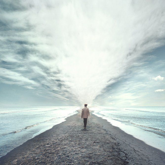 A man is walking along a beach towards the ocean.