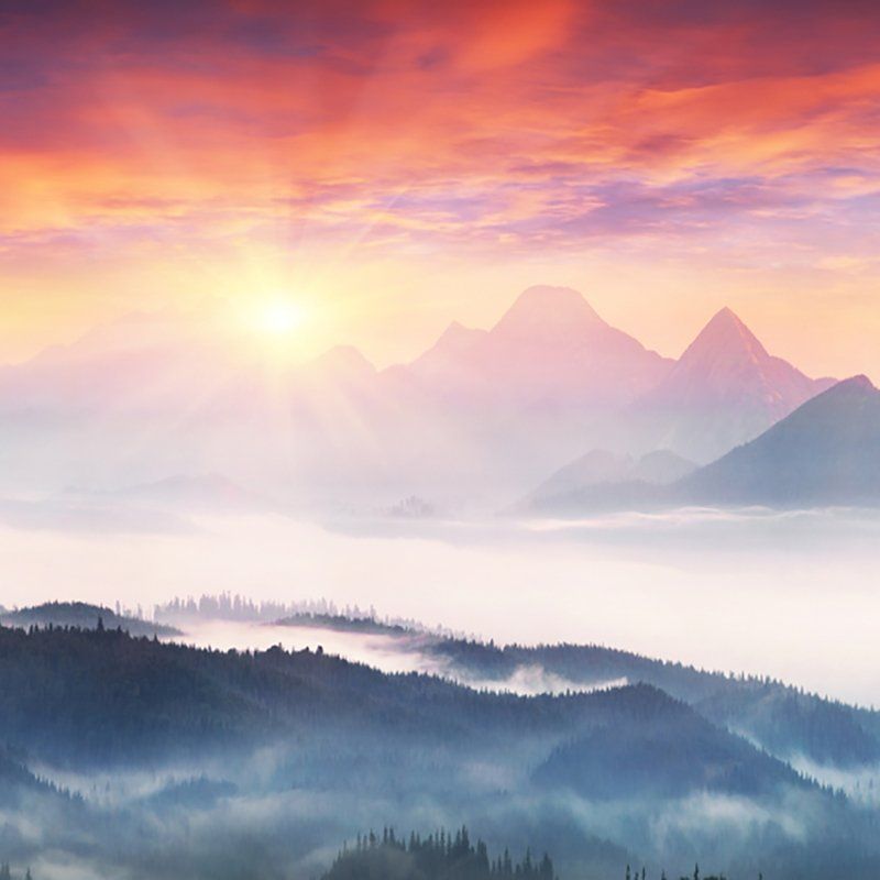 The sun is shining through the clouds over the mountains