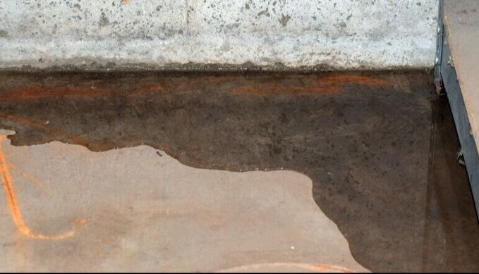 A close up of a puddle of water on a concrete floor. Northglenn, Colorado accountable home services