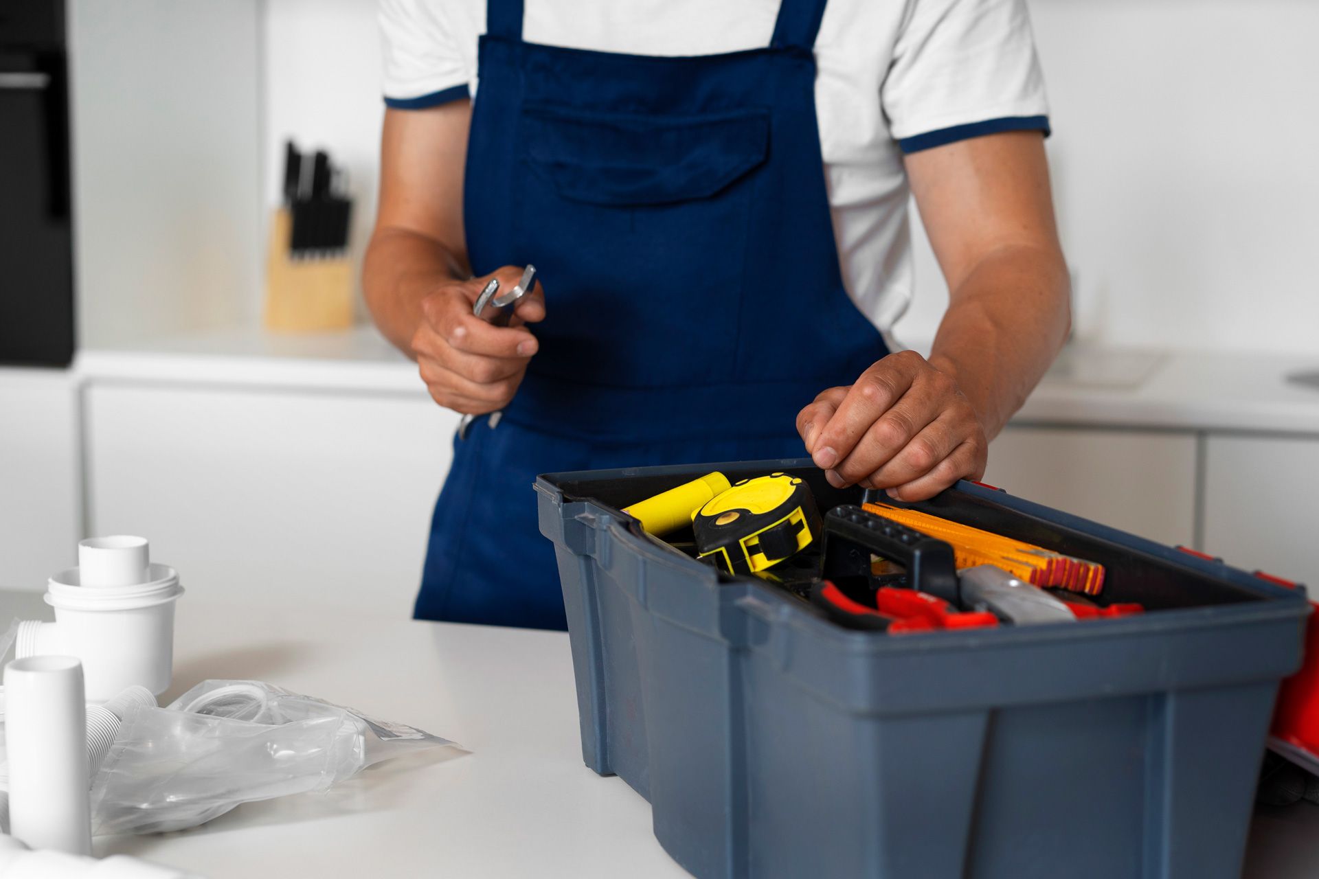 A man is holding a wrench next to a toolbox filled with tools.