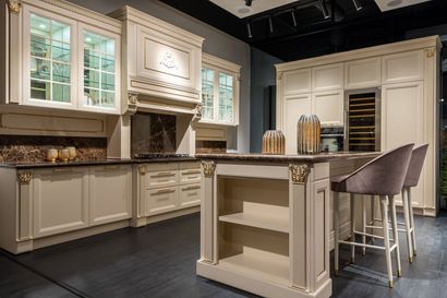 Modern white kitchen with a large island, wood paneling, and fresh produce on the counter.