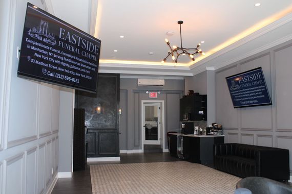Eastside Funeral Chapel's Elegant lobby with white paneled walls, chandeliers, and black signage on both sides.
