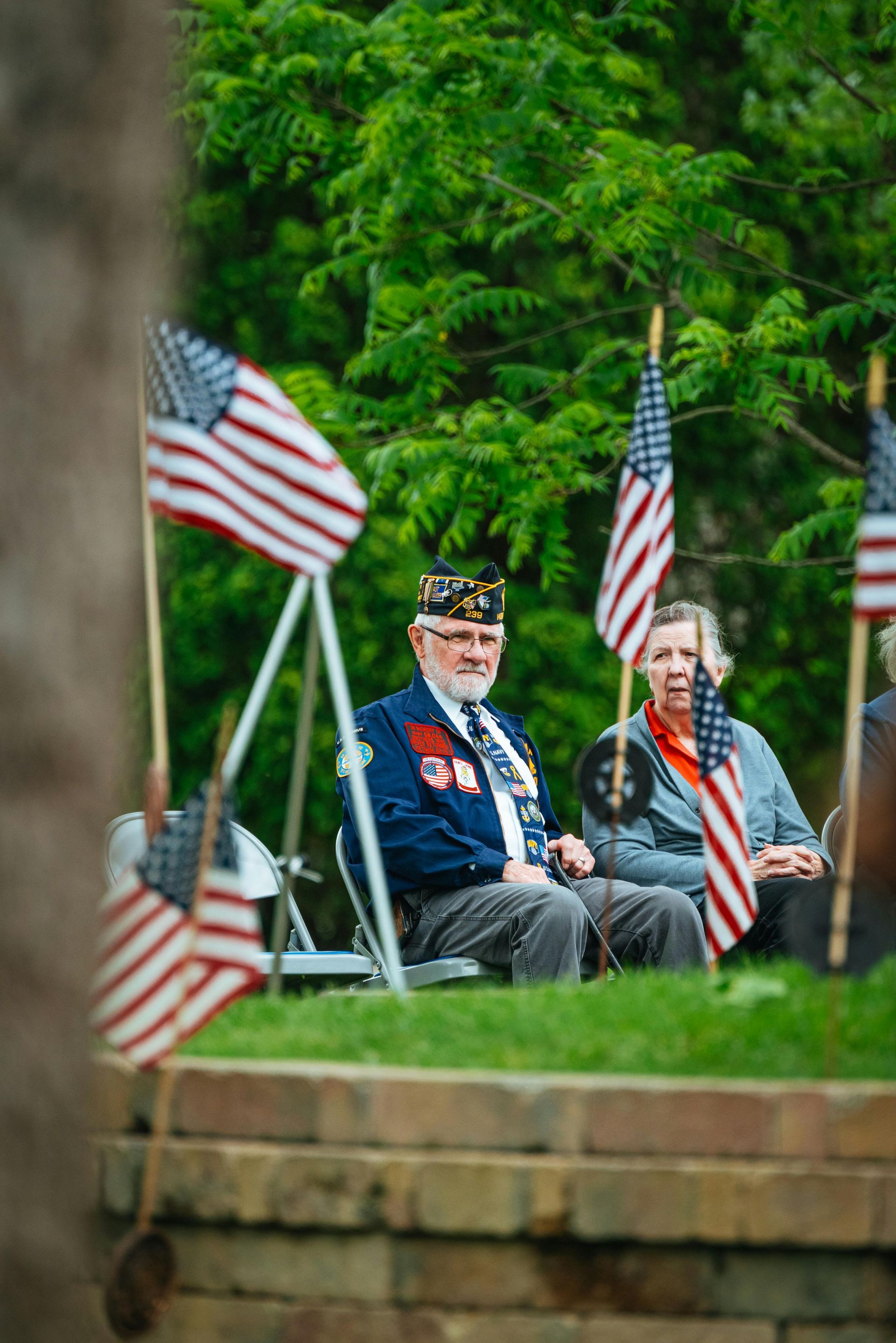 Veterans seated among American flags in a green park setting