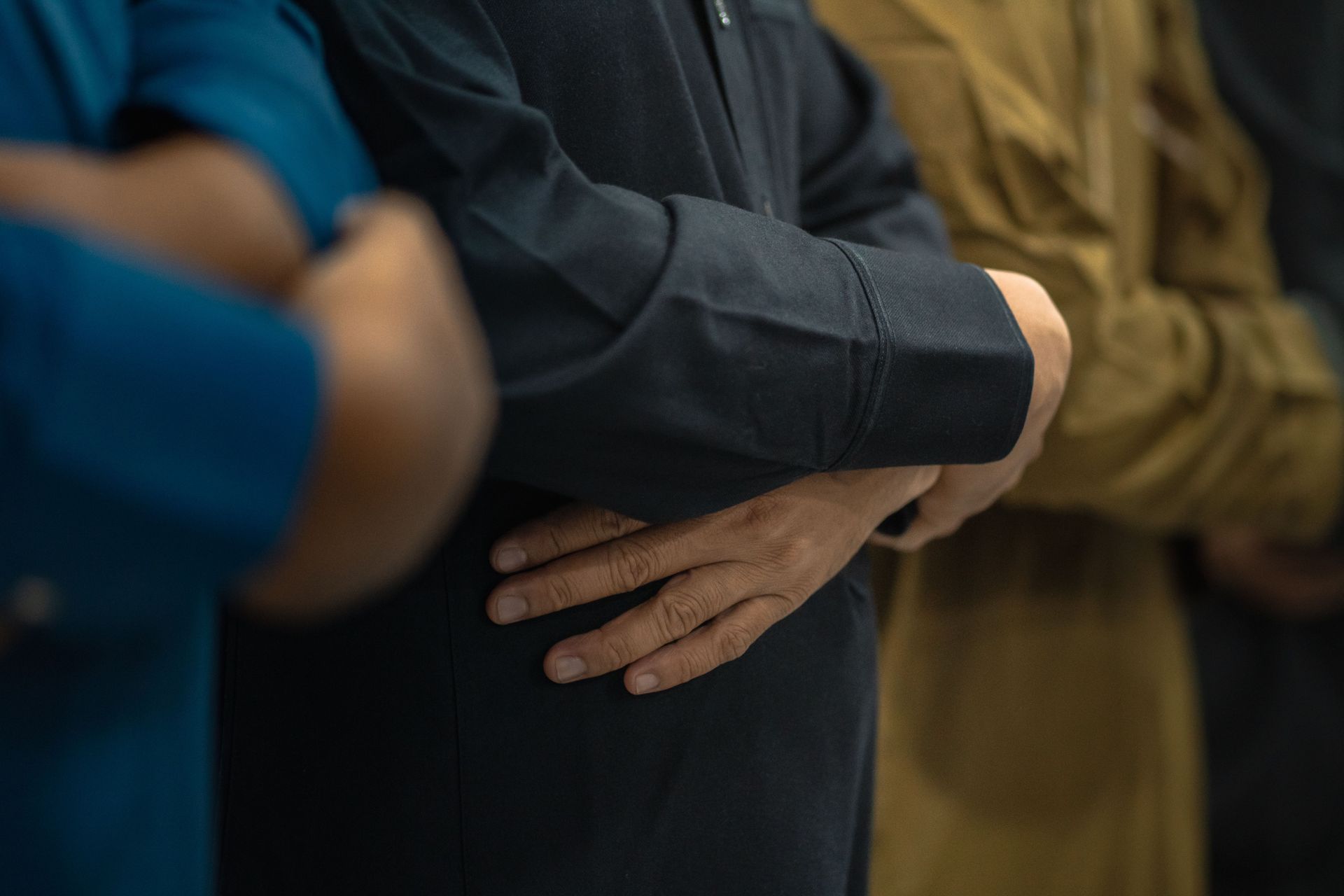 People standing close together with arms crossed in a dim indoor setting