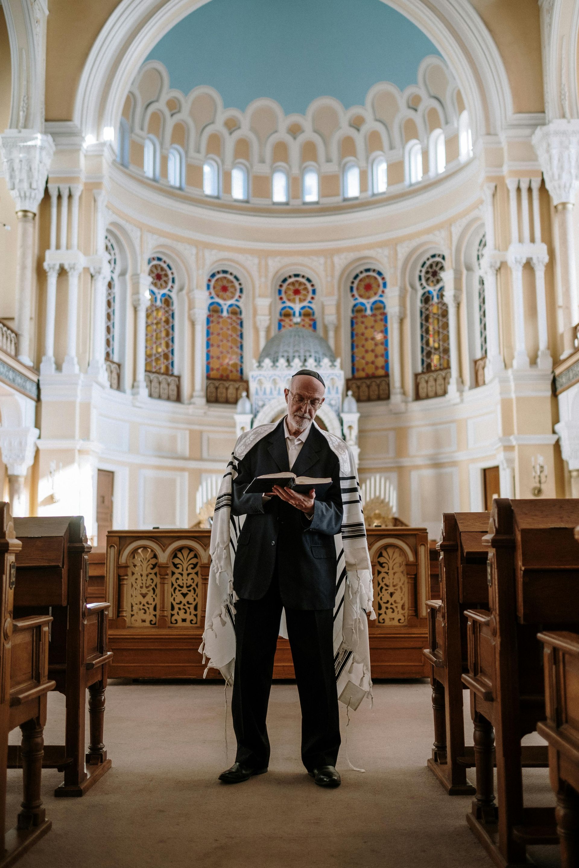Person standing in a church aisle reading from a book under a blue-domed ceiling