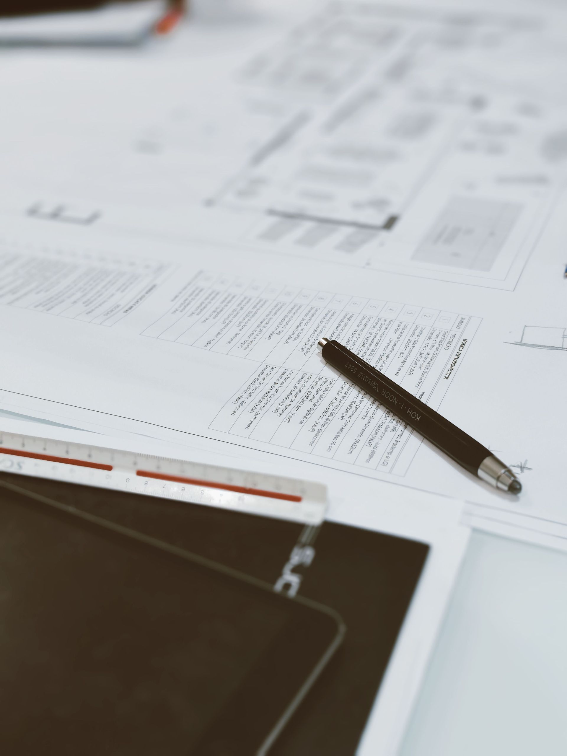 Spreadsheet and printed documents on a desk with a pen in the foreground