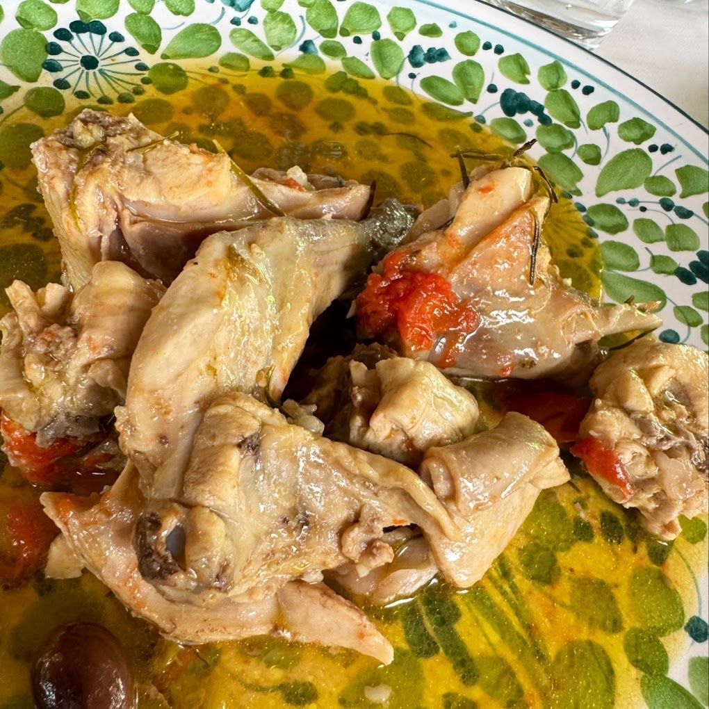 Piatto con pezzi di pollo cotto in salsa rossa su un piatto decorato con foglie verdi e gialle.