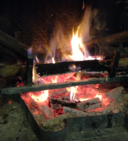 Tronchi che bruciano in un braciere di metallo con fiamme brillanti e braci ardenti di notte