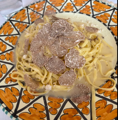 Pasta in salsa cremosa con scaglie di tartufo su un piatto decorato.