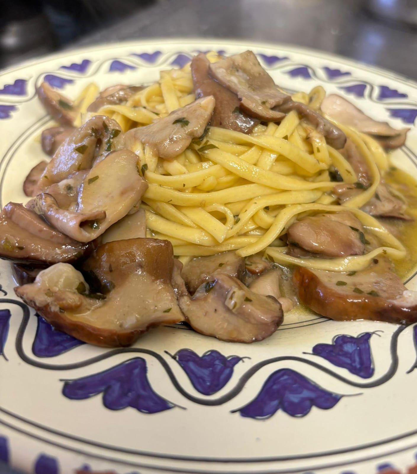 Pasta con funghi a fette su un piatto decorato in bianco e blu.