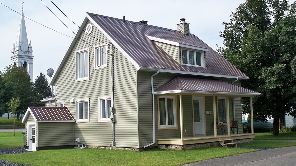 Two-story green house with brown roof