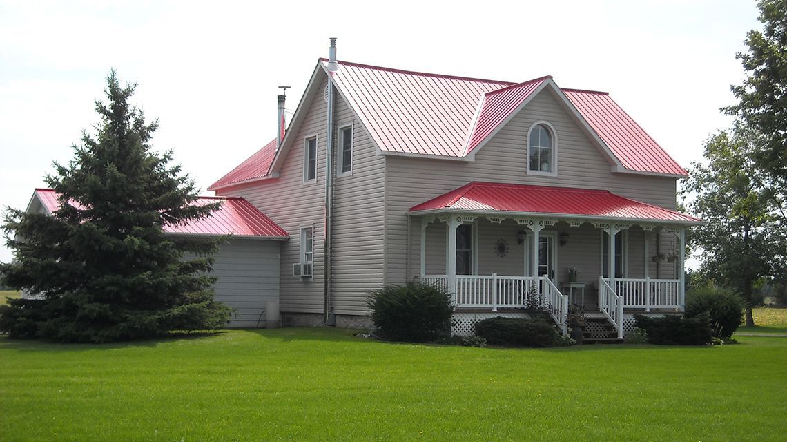 Two-story beige house with red metal roof