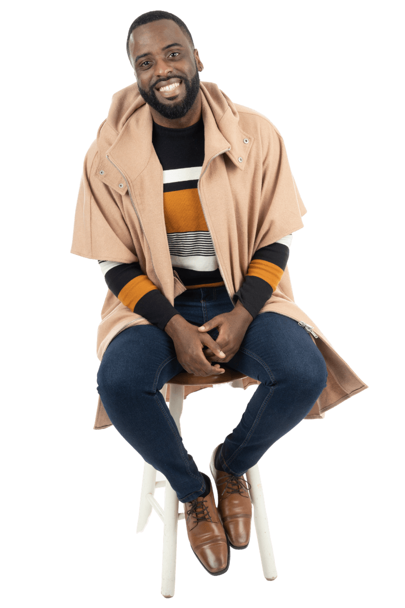 Tony Shavers III, cheerfully smiling while sitting on a stool