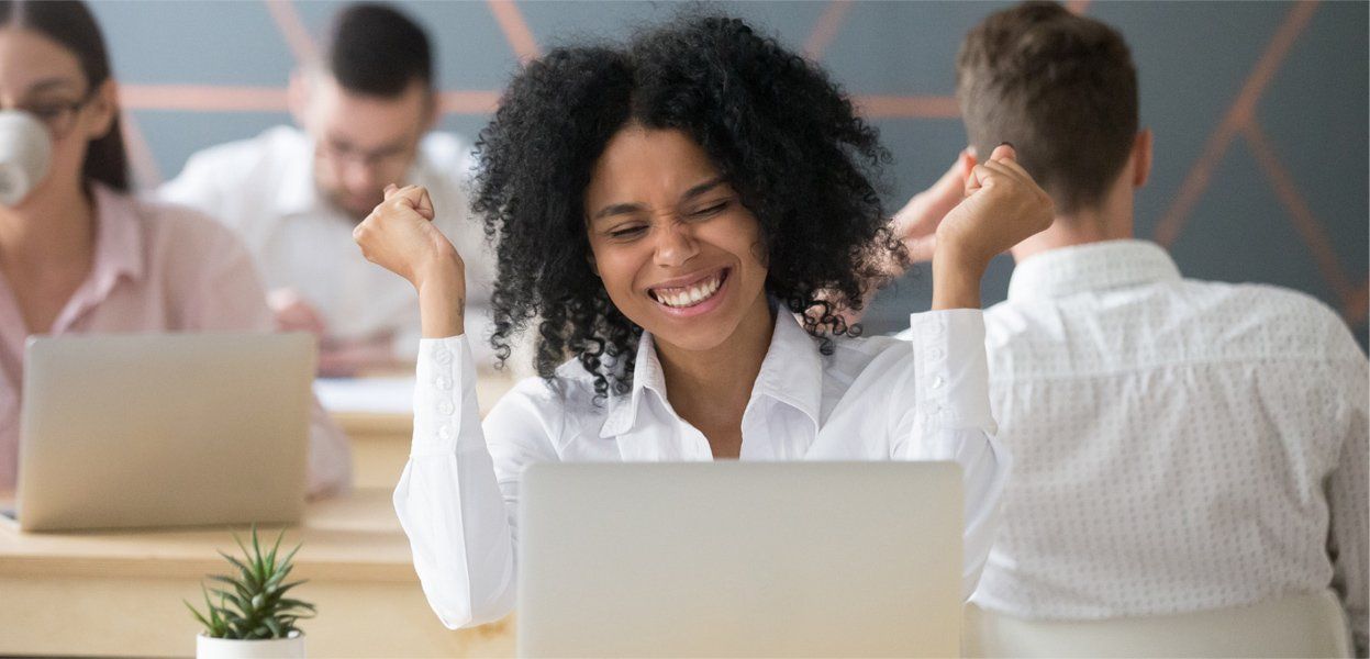 fulfilled and happy employee in the office while using her laptop
