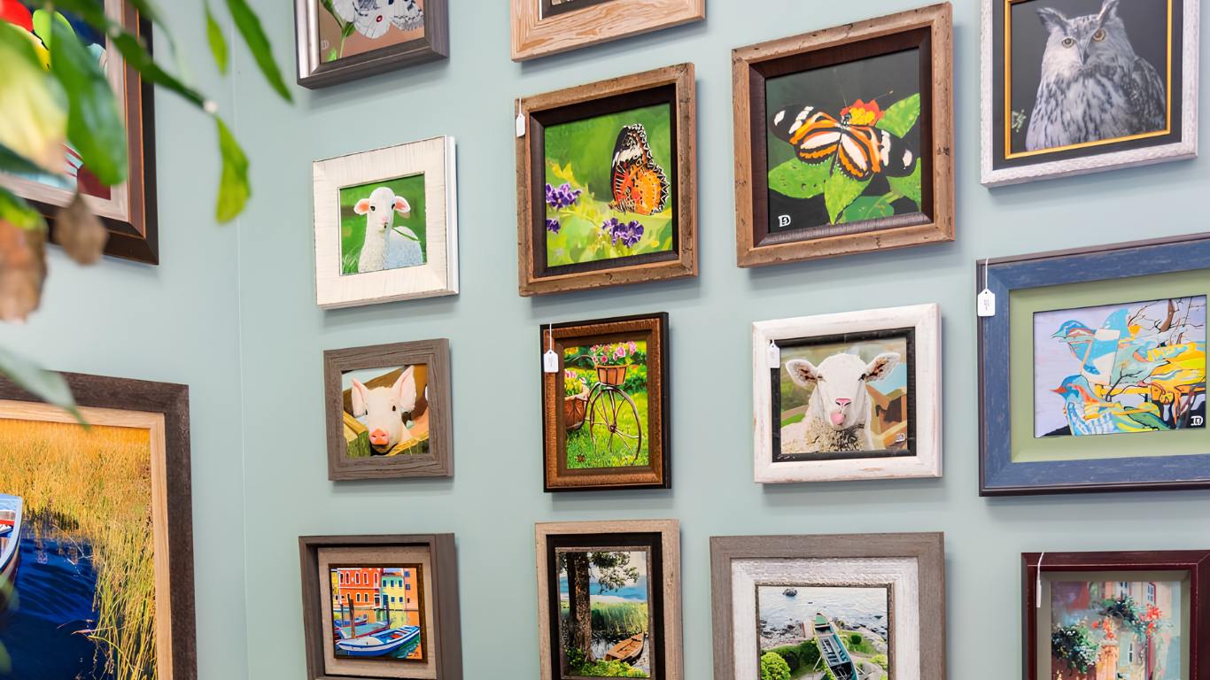 A wall covered with small colorful framed animal and nature paintings.