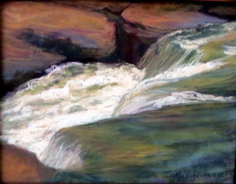 Waterfall cascading over rocks into a green pool, with a dark rocky backdrop.