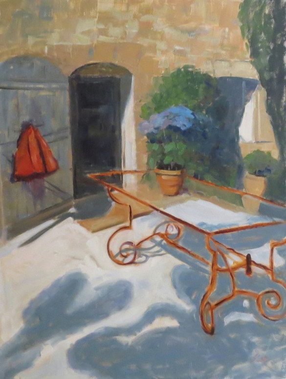 Sunlit courtyard with an orange iron bench, stone walls, and potted blue-green plants.