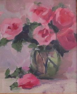 Pink flowers in a vase with green leaves against a soft pink background.