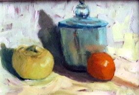 Still life with a blue jar, yellow fruit, and a red tomato on a pale surface.
