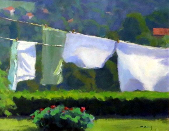White laundry hanging on a clothesline in a sunny green garden