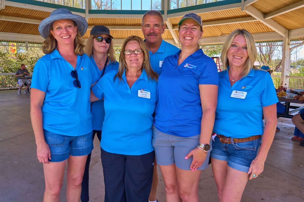 A group of people wearing blue shirts are posing for a picture.