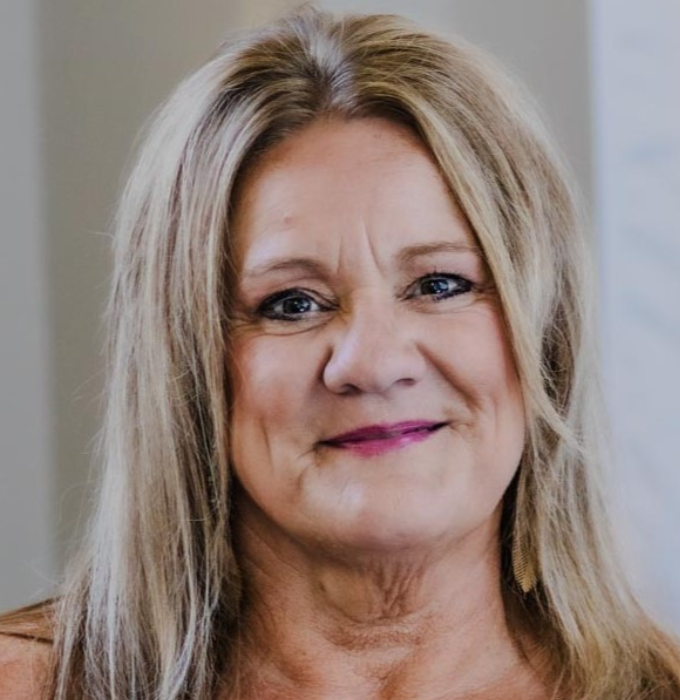 A woman with long blonde hair is smiling for the camera.