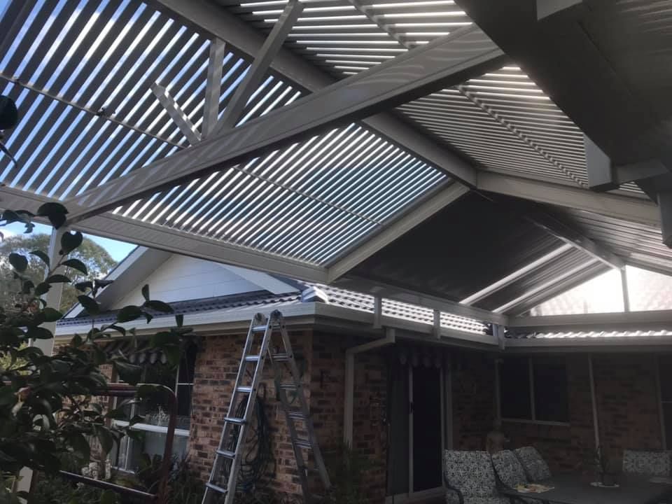 A ladder is sitting under a roof of a house.